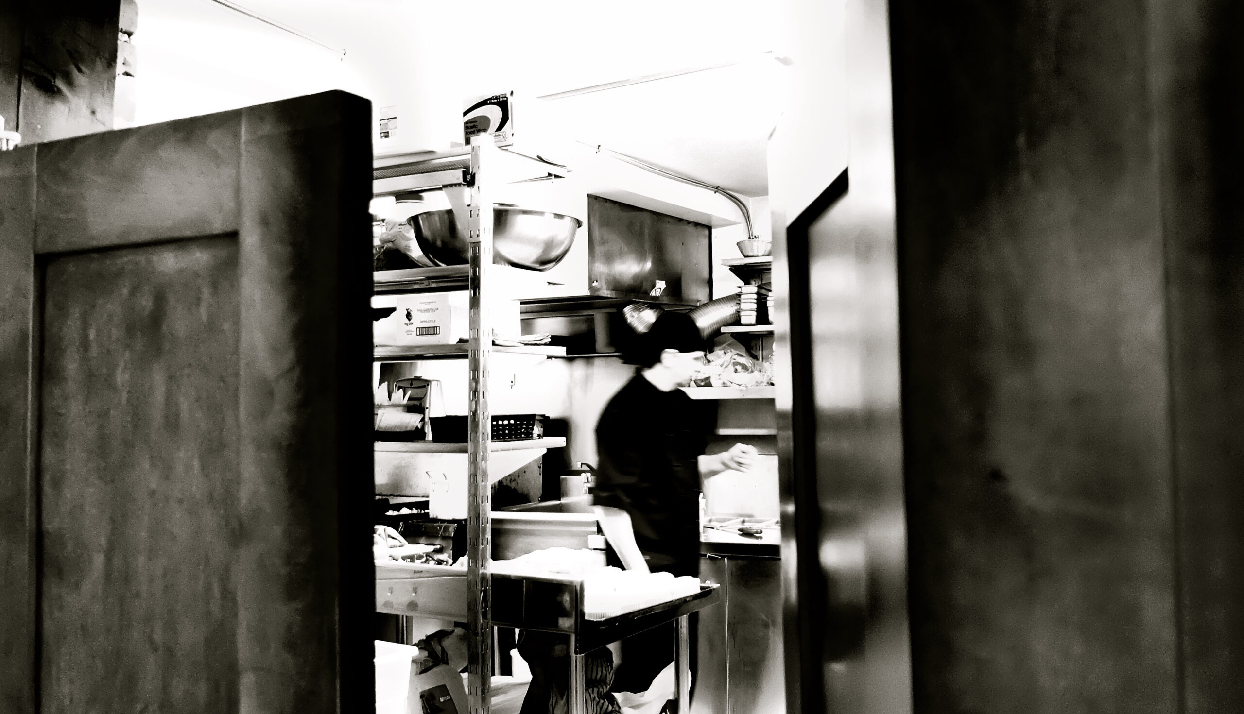 Photo en noir et blanc d'une cuisine du restaurant avec un cuisinier